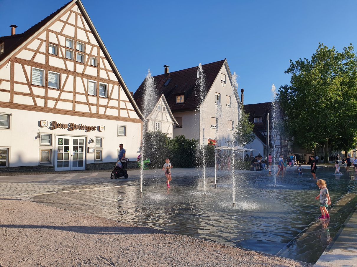 Im Vordergrund der Bereich Seelesplatz in Herrenberg mit Wasserflächen, die zum Erleben einladen, im Hintergrund die angrenzende Altstadt. 