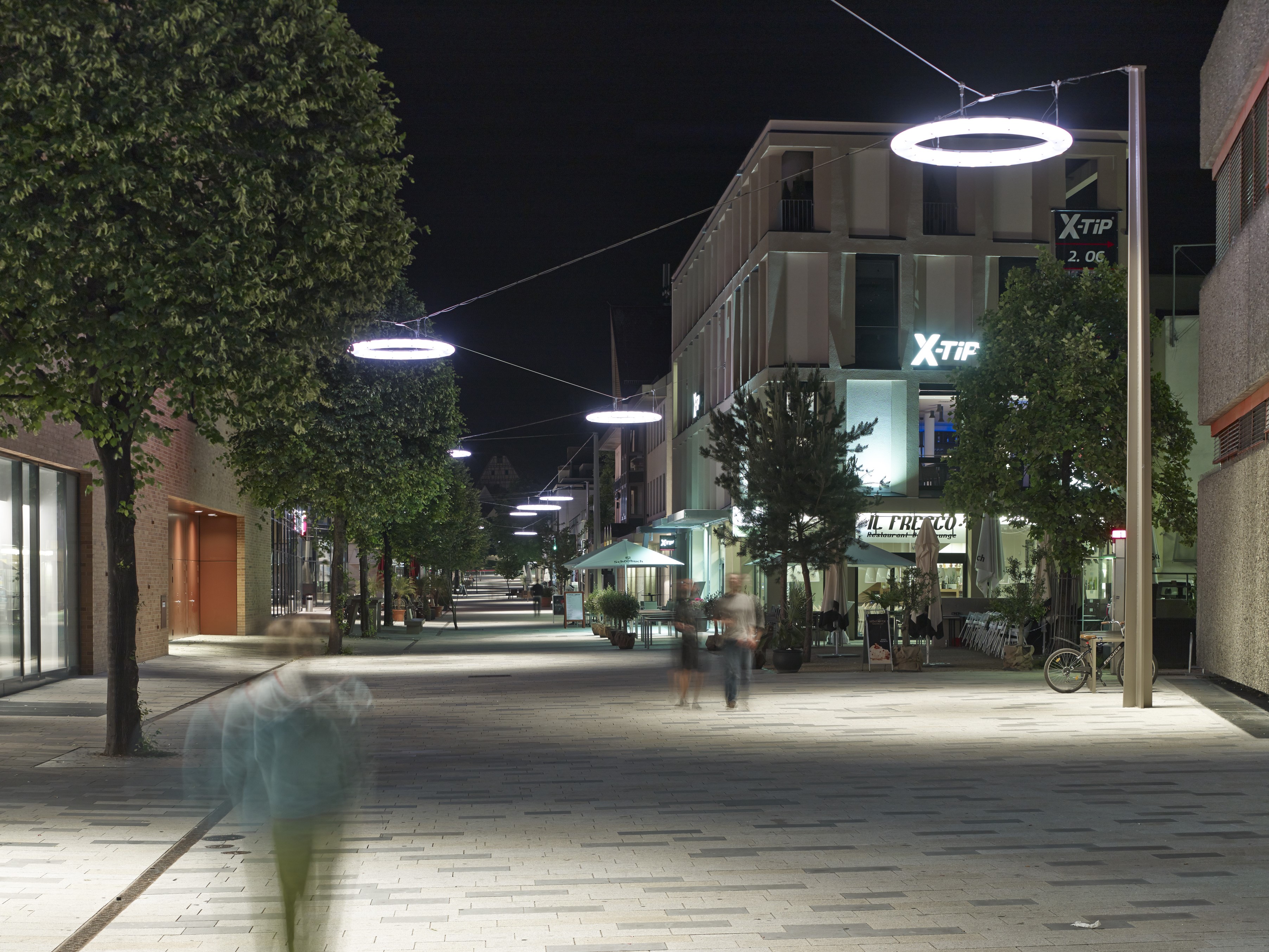 Blick bei Dunkelheit in die Fußgängerzone "Neue Meile" in Böblingen: Diese wird von radförmigen Straßenleuchten erhellt, die an Seilen über der Fußgängerzone hängen.
