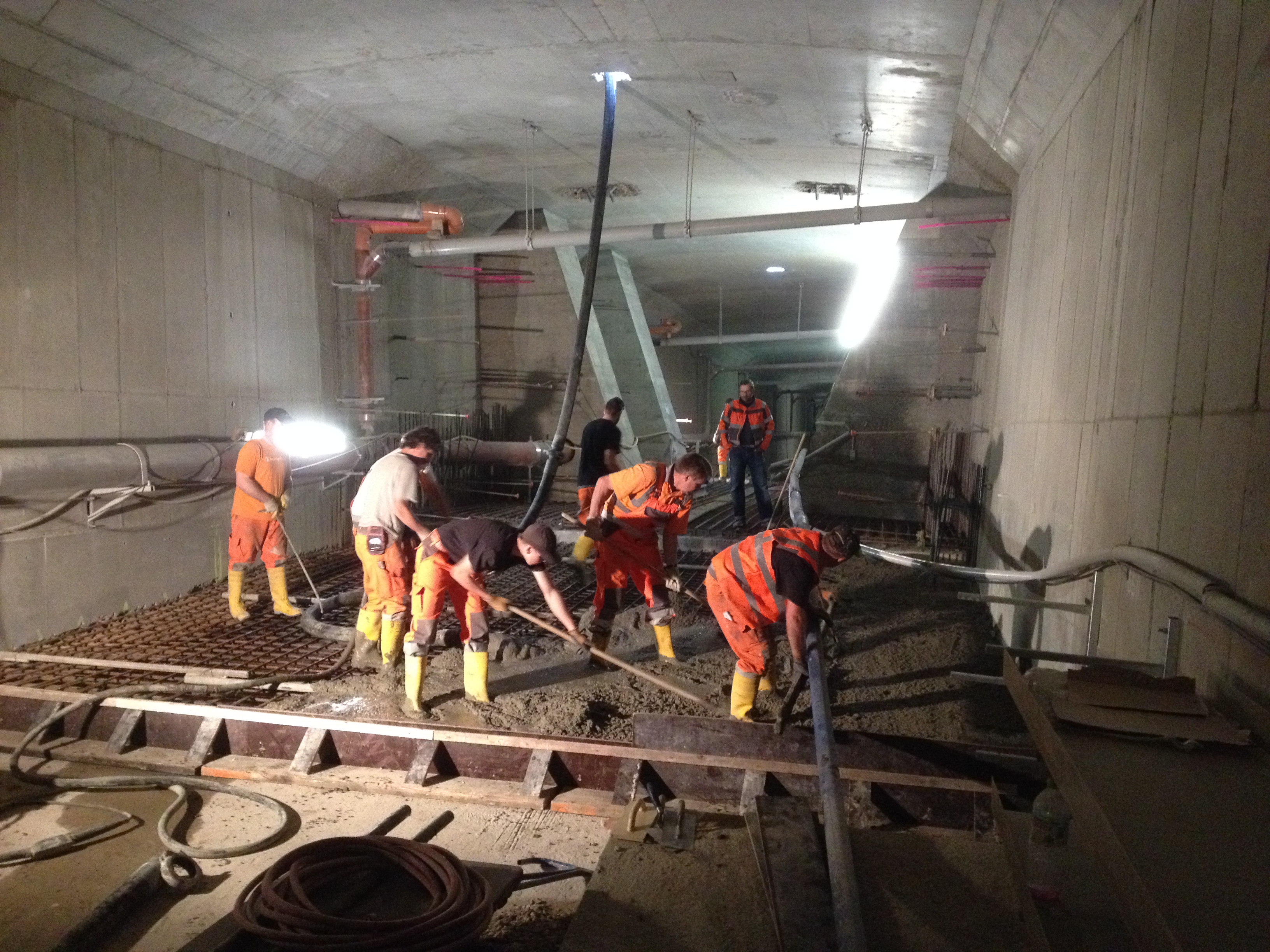 Das Bild zeigt einen Blick in den Hohlkörper der Kochertalbrücke, in dem Facharbeiter damit beschäftigt sind, Beton auf der Bodenplatte zu verteilen, um diese zu verstärken.