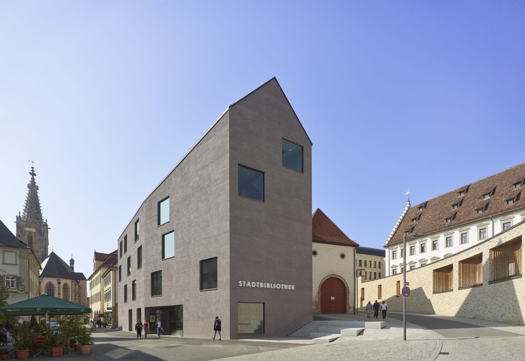 Blick auf eine Straßengabelung in Rottenburg: In der Bildmitte befindet sich der Neubau der Stadtbibliothek, links von ihr geht es in die Fußgängerzone, rechts von ihr führt eine Straße zum Bischöflichen Ordinariat.