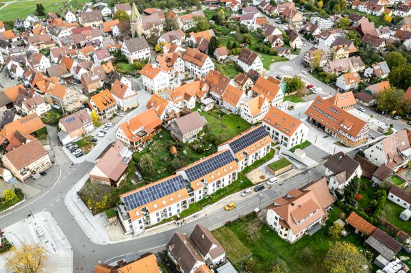 Die neue Ortsmitte in Walddorfhäslach mit der Neugestaltung des öffentlichen Verkehrsraums, drei denkmalgeschützten Gebäudekomplexen, neuen Wohnanlagen mit Photovoltaikanlagen auf den Dächern und einer Geothermieanlage.