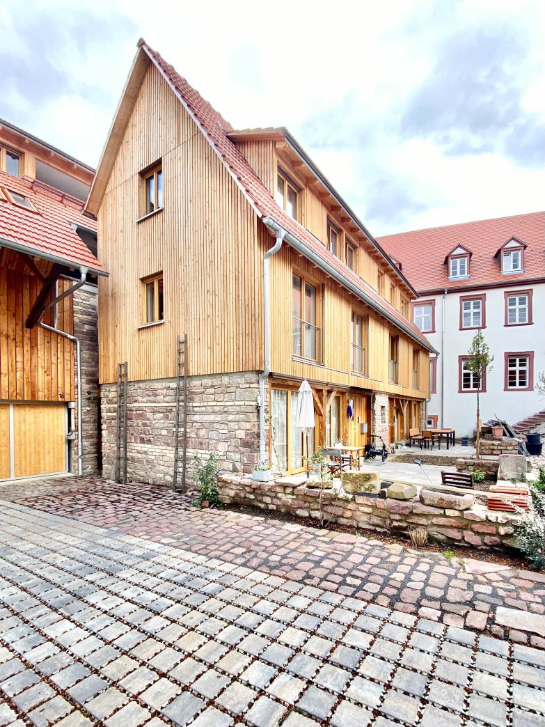 Sanierung der historischen Hofanlage unter Verwendung historischer Materialien wie alte Mauer- und Pflastersteine zum  Erhalt des Erscheinungsbildes der Gebäude im mittleren Teil des Bildes erkennbar.