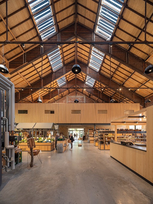 Markthalle mit regionalen Produkten unter Einbeziehung historischer Bauteile wie Fenster und Tore.