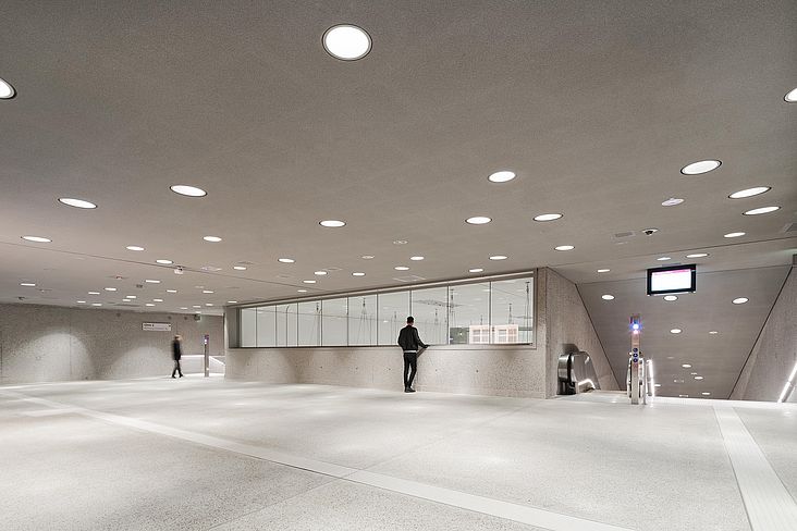 Unterirdische Stadtbahn Karlsruhe mit weißen Raumschalen auf Bahnsteigebene und abgehängter Stahlseilkonstruktion mit integriertem Lichtkonzept.