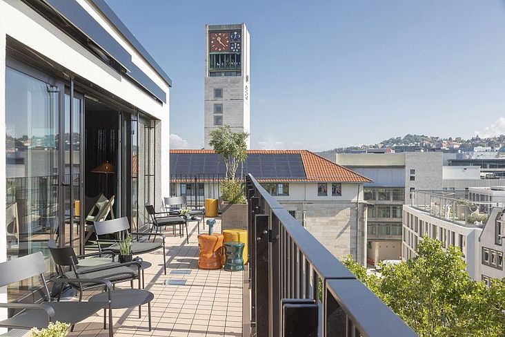 Die steinerne Lochfassade mit bodentiefen Fenstern und die zweigeschossige Aufstockung in leichter Holzbauweise mit Rooftop-Bar lassen die Fassade des ehemals konventionellen Bürogebäudes aus den 1960er Jahren in neuem Glanz erstrahlen. 