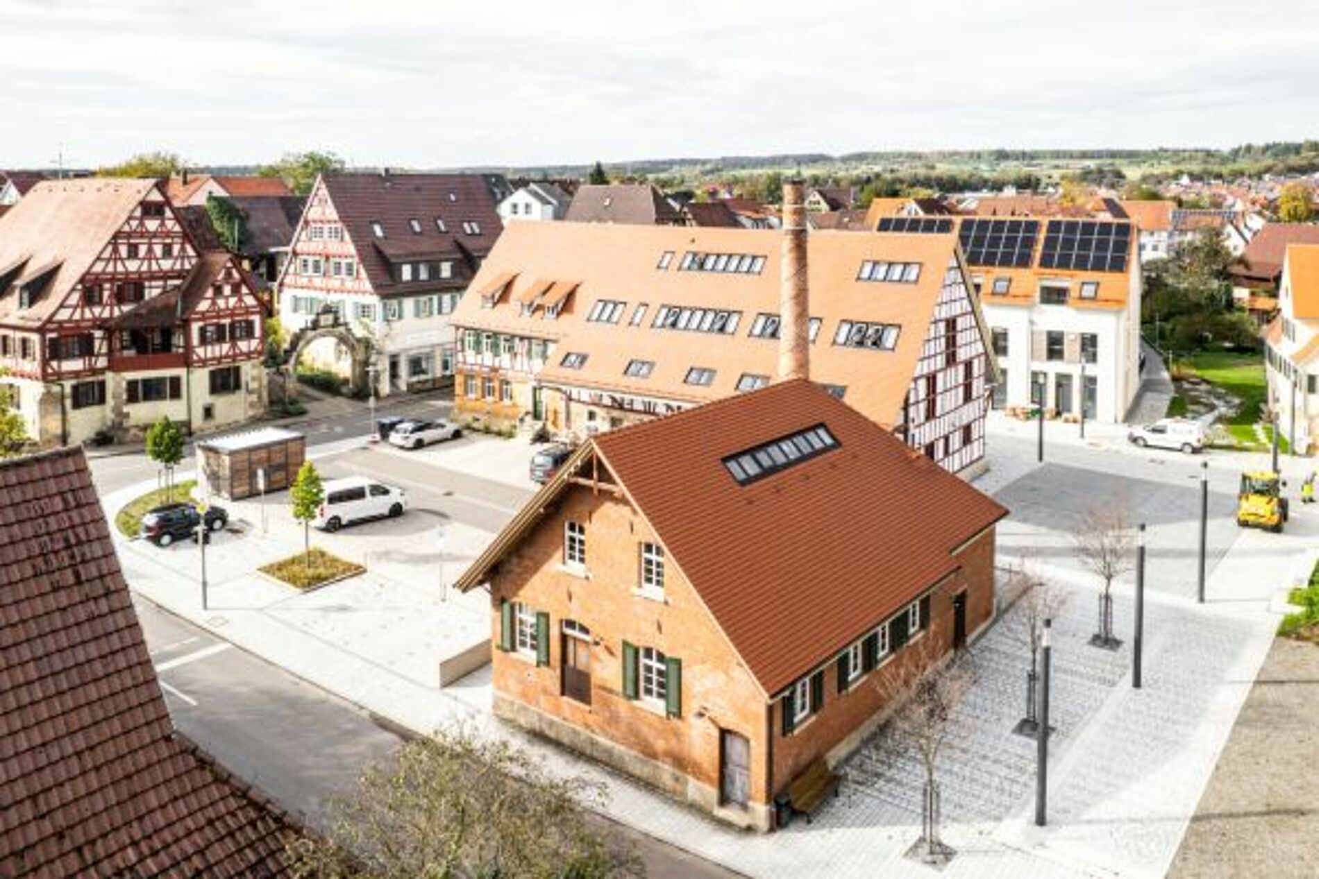 Die neue Ortsmitte in Walddorfhäslach mit der Neugestaltung des öffentlichen Verkehrsraums, drei denkmalgeschützten Gebäudekomplexen, neuen Wohnanlagen mit Photovoltaikanlagen auf den Dächern und einer Geothermieanlage.